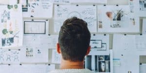 A man estimating bids on a wall with hanged papers