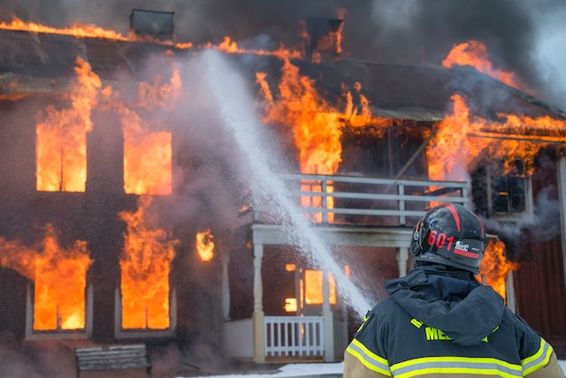 A firefighter in front of a burning building
